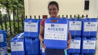 Distribution d'aide humanitaire en réponse aux inondations de juillet aux Philippines. Une jeune femme reçoit un jerrycan d'eau lors d'une distribution d'aide humanitaire.