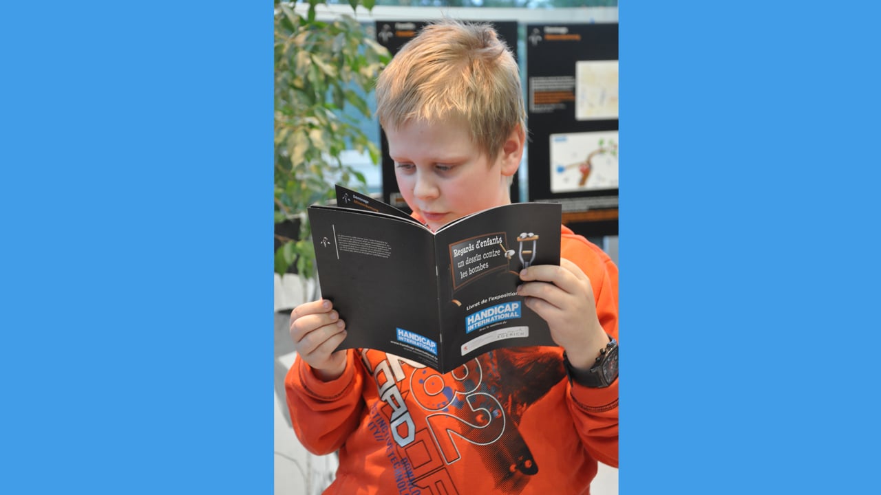 Un élève du cycle 4 de l’école fondamentale de Koerich en train de découvrir le livret de l’exposition « Regards d’enfants » reprennant l’ensemble des dessins produits par les 60 élèves ayant participé au projet.
